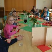 Kinder und Eltern sitzen am gedeckten Tisch und essen Fladenbrot