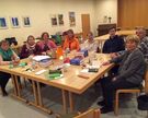 Mitglieder des Kirchort-Team sitzen am Tisch, auf dem Tisch sind Teetassen, Bibeln, Zettel, Stifte, Schokolade