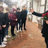 Pfarrer Volkwein mit Rosen in der Hand, Jugendliche hören zu