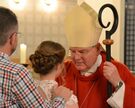 Weihbischof Bongartz firmt ein Mädchen, der Pate legt die Hand auf ihre Schulter