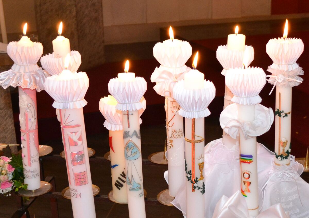Brennende Kommunionkerzen auf einem gemeinsamen Kerzenständer