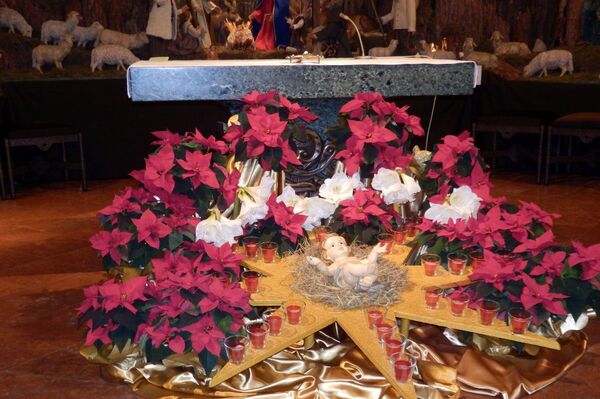 Jesuskind aus der Krippe liegt inmitten von Weihnachtssternen vor dem Altar