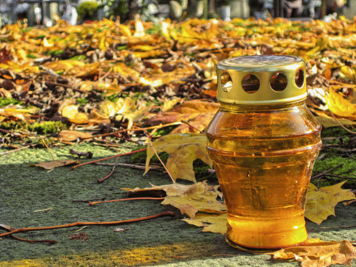 Ein Grablicht in buntem Herbstlaub auf dem Boden
