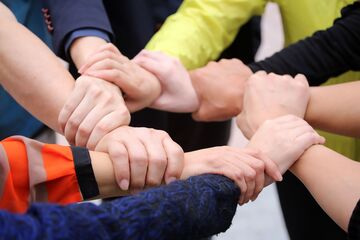 Hände von mehreren Menschen, die gemeinsam einen Kreis bilden