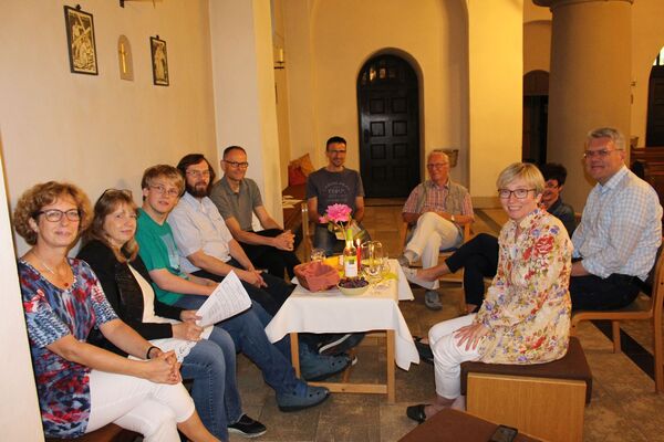 Teilnehmer des Abends zum Thema "Komm, heiliger Geist" sitzen in der Kirche um einen gedeckten Tisch